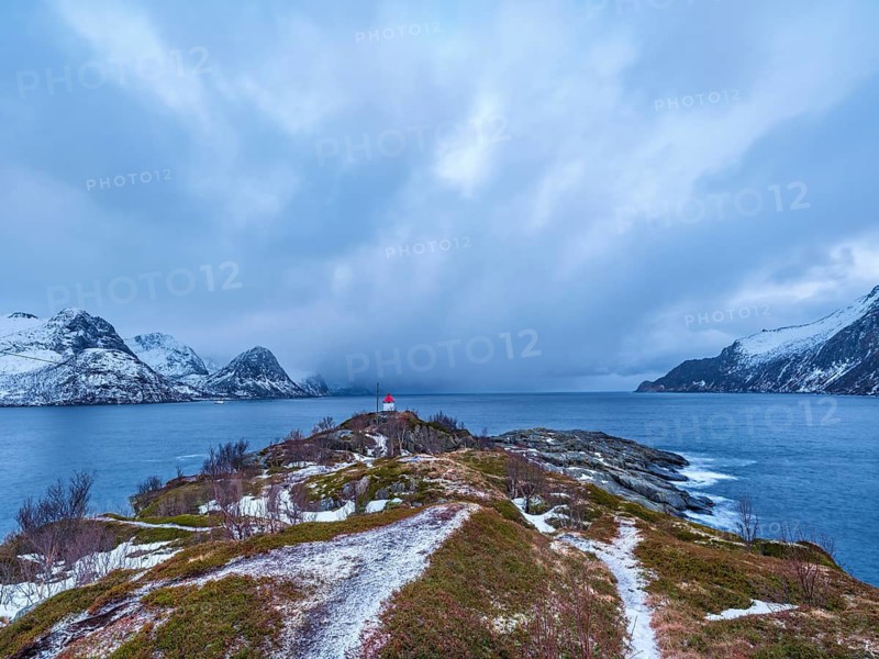 Small lighthouse at the end of Husøy island with a view across the fjord to the sea, Senja island, Troms, Norway
