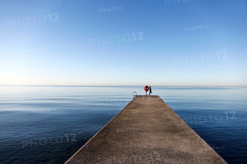 Northern lights, atmosphere with soft blue as far as the horizon, a woman standing on a jetty on the beach on the island of Fehmarn, 08.04.2026, Fehmarn, Schleswig-Holstein, Germany