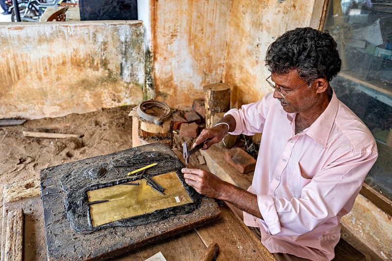 Man doing traditional crafts with tools on metal plate in rustic workshop, A craftsman working in Sigiriya in Sri Lanka