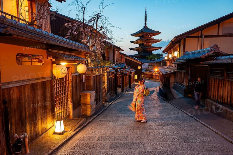 Japanese woman in kimono in an alley, Yasaka dori historic alleyway in the old town with traditional Japanese houses, five-story Yasaka Pagoda of the Buddhist Hokanji Temple in the back, evening mood, blue hour, Higashiyama, Kyoto, Japan