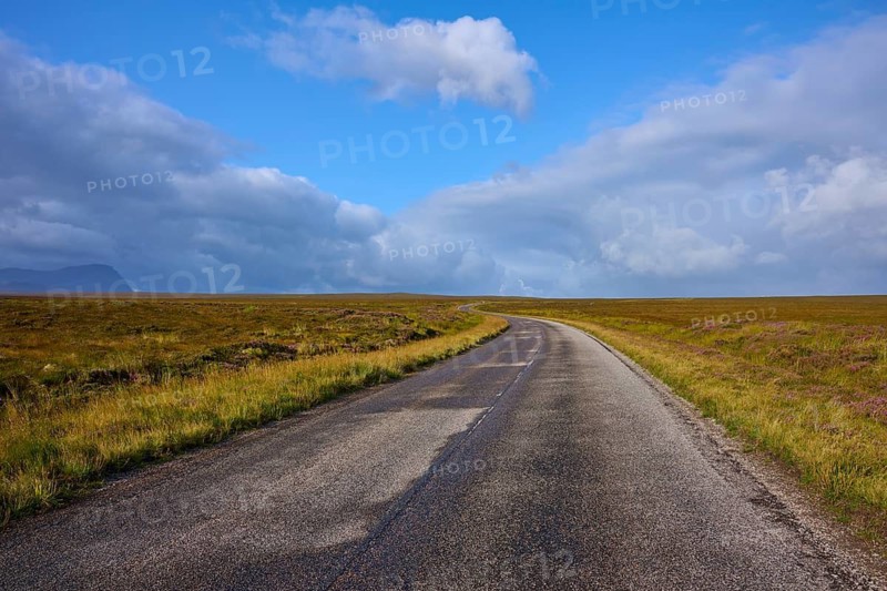 A deserted paved road stretches through an open landscape against a cloudy sky, Tongue, Lairg, Scotland, United Kingdom, Great Britain