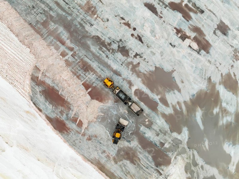 Excavator and lorry at a harvesting pan of the Walvis Bay Salt works. Aerial view. Drone shot. Walvis Bay, Namibia