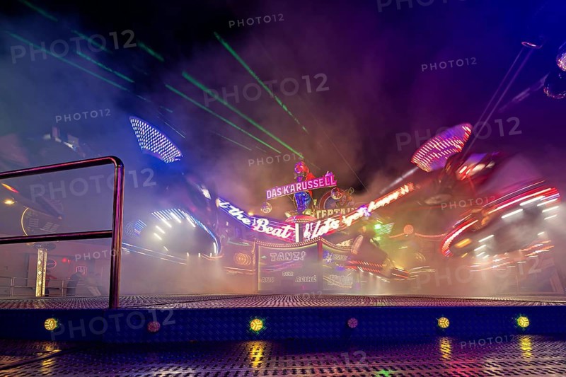 A carousel wrapped in fog at night, illuminated by colorful neon lights in motion, carousel and hustle and bustle of summer profit in Eisenach