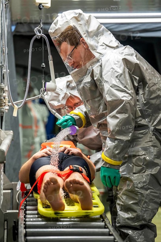 Decontamination of injured persons after an assumed accident involving hazardous substances, fire brigade and aid organisations practise setting up and operating a decontamination station, injured persons are sighted and then washed in a special shower tent to remove possible hazardous substances and chemicals in order to avoid further injuries, the emergency services wear special, ventilated protective suits, large-scale exercise by the Essen fire brigade