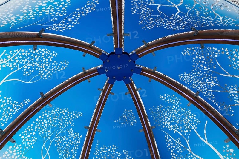 Close-up of backlit blue tinted plexiglass and curved wood panels canopy decorated with white maple leaves in the wind theme motifs inside interactive cocoon rocking chair made by Olivier Landreville, Horizon Art Installation, Ile des Moulins, Old Terrebonne, Quebec, Canada