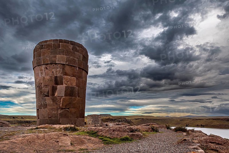 A large stone tower against a dramatically cloudy sky, The Chullpas of Sillustani near Puno in Peru