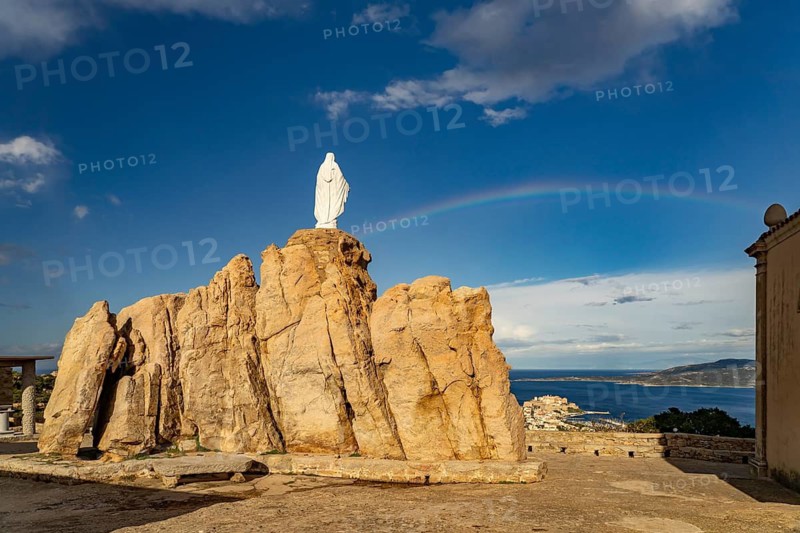 Rainbow on the statue of the Virgin Mary on a rock next to the Notre Dame de la Serra pilgrimage chapel in Calvi, Balagne, Corsica, France