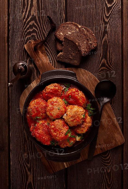 Beef meat balls in tomato sauce, with spices and herbs, on a wooden background, top view, no people