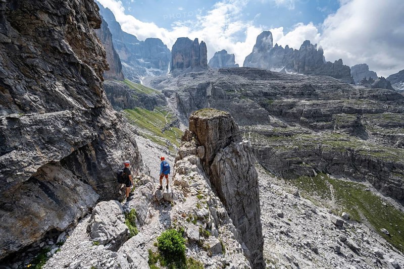 Two mountaineers in front of a picturesque mountain landscape with rocky peaks, Via Ferrata SOSAT via ferrata, Cima Tosa summit in the back, Brenta Mountains, Trentino, Italy