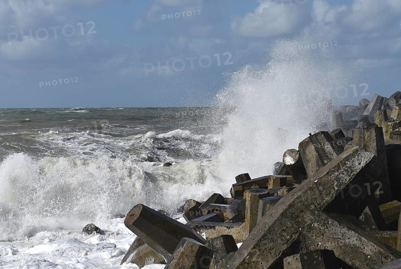 Foaming waves hit rough concrete structures on the coast