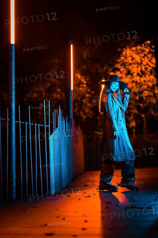 Girl in a hat walking at night in a park, pensive and enjoying the tranquility without people, blue light