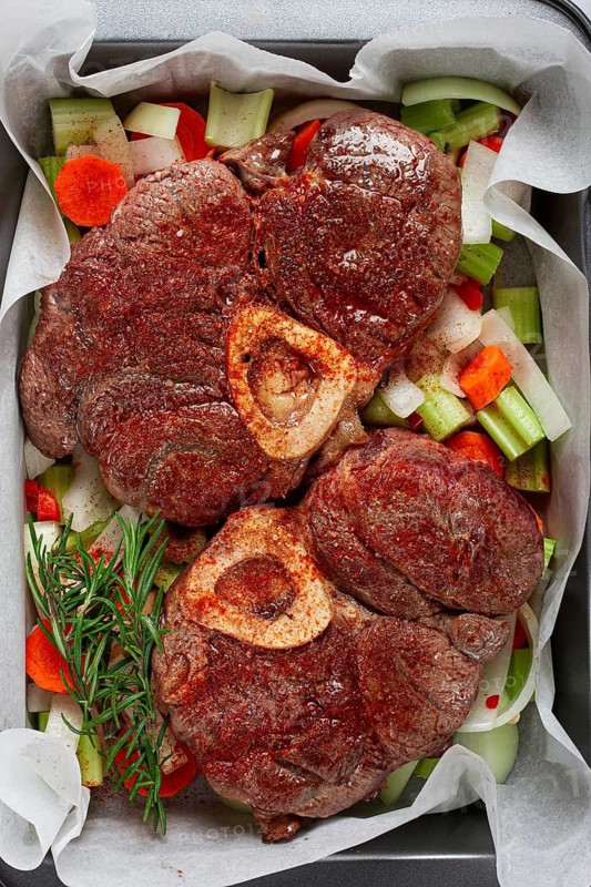 Fried meat on the bone, raw, chopped vegetables, ingredients in the oven, for cooking ossobuco, top view, no people