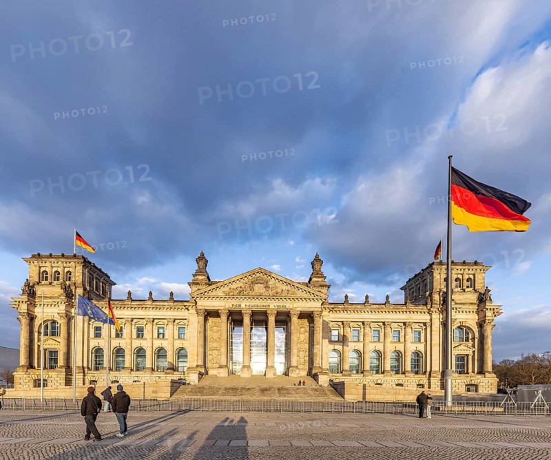 Reichstag building Berlin with German flags. Exterior view with dark clouds. Berlin, Germany