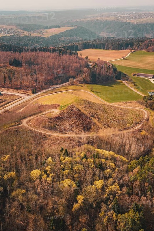 Wide view of a hilly landscape with forests and fields, bordered by a winding path, old deposit in front of PV Bau, Lindenrain, Calw, Germany
