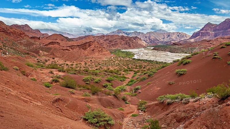 Red rocks and valleys with vegetation under a clear, blue sky, the landscape and colorful rock formations of the Quebrada de Cafayate near Salta in Argentina