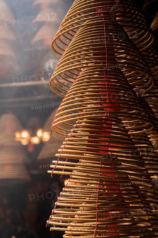 Detailed view of spiraled incense coils with red threads, symbolizing prayers and celebrations during Chinese New Year in Hong Kong. The coils emit fragrant smoke, contributing to the festive atmosphere