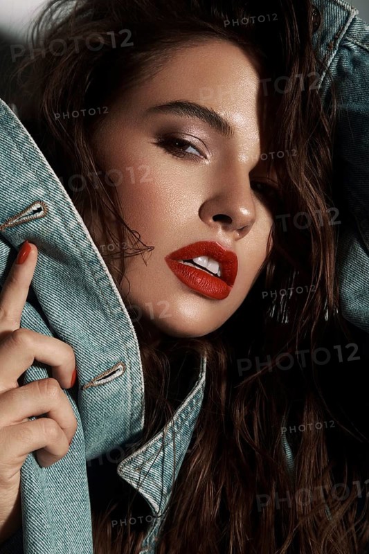Beautiful sexy girl with bright makeup, red lips, wet hair in a denim jacket. Beauty face. Photo taken in studio