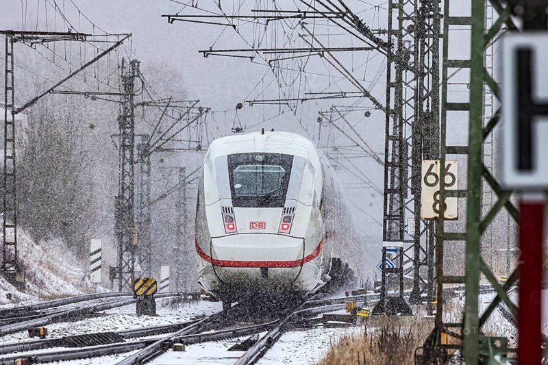 ICE traveling through a winter landscape in snowfall. A train on the line in the Deutsche Bahn Amstetten rail network, Baden-Württemberg, Germany