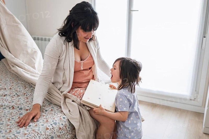 A joyful mother and her big sister daughter enjoy bonding time in a cozy home setting, sharing laughter and happiness, representing the essence of a loving young family
