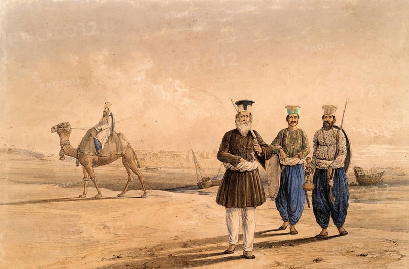 Two men and a rider riding a camel in a vast sandy landscape