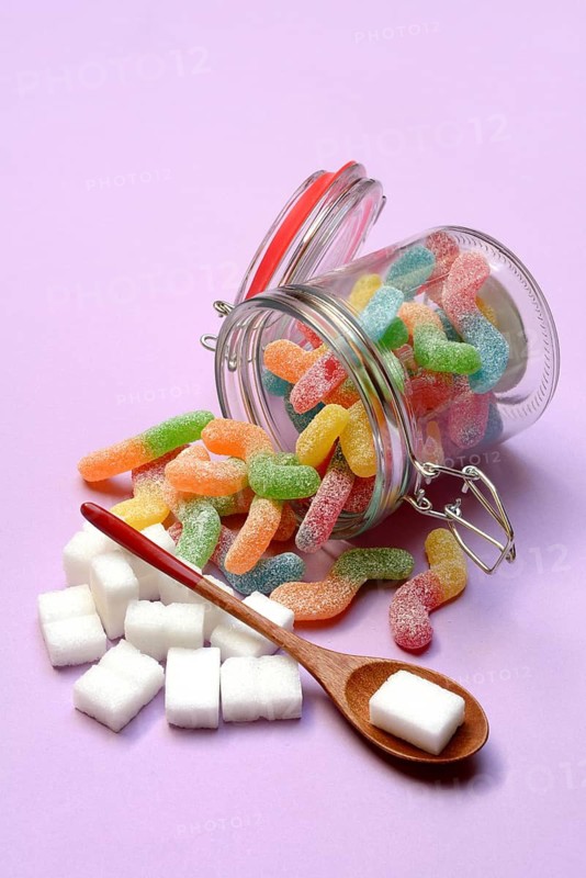 Lots of colorful jelly sweets in glass containers and sugar cubes, sugar consumption