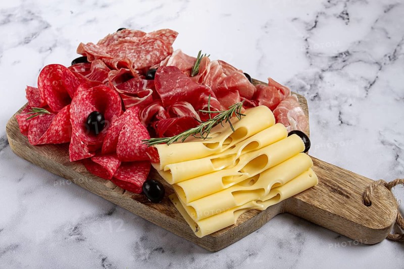 Assorted meat, appetizer, prosciutto, salami and ham, with maasdam cheese and olives, on a wooden board, breakfast, top view, close-up, no people