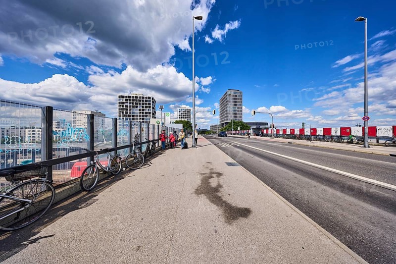 Car bridge and footbridge, metal railings, glass elements, sidewalk, road, lanes, lantern, road marking BUS, bicycles, general architecture, high-rise buildings, pedestrians as a secondary motif, blue sky, white and dark gray cumulus clouds, Friedenheimer bridge, Munich, state capital, district-free city, Bavaria, Germany