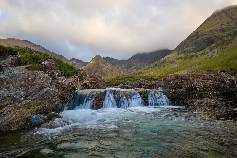Small waterfall in a mountainous landscape under cloudy sky with clear water streams, Fairy Pools, Grula, Isle of Skye, Scotland, United Kingdom, Great Britain