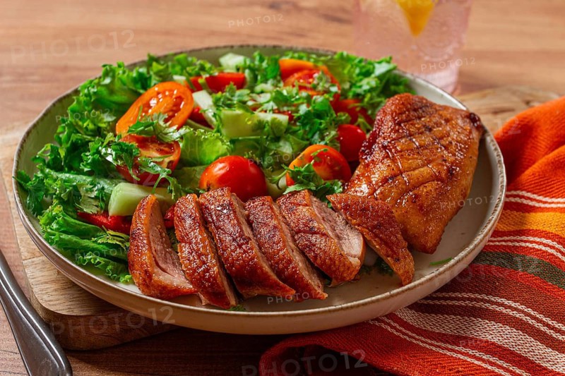 Delicious grilled duck breast served with fresh garden salad and cherry tomatoes at a rustic dining table