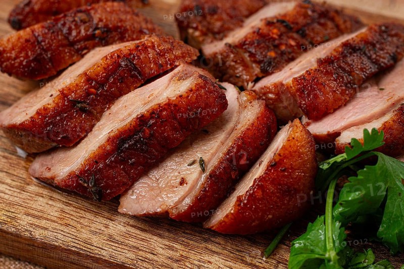 Roast duck breast, sliced, on a wooden chopping board, close-up, no people