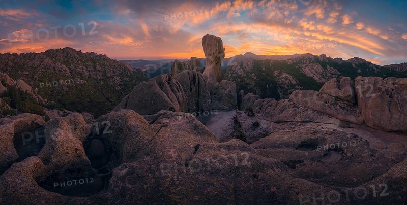Stunning sunset at Pedriza, Sierra de Guadarrama, Madrid, highlighting dramatic rock formations in Jardin de los Caballeros beneath vibrant clouds against a fading sky