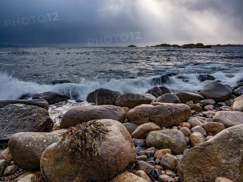 Waves wash around large round rocks on the beach, Svolvaer, Lofoten, Norway