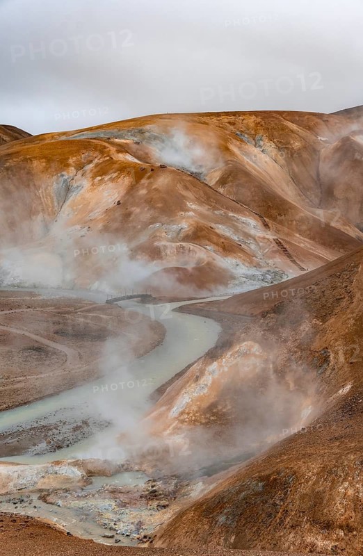 Bridge and steaming streams between colourful rhyolite mountains and snowfields, Hveradalir geothermal area, Kerlingarfjöll, Icelandic Highlands, Iceland