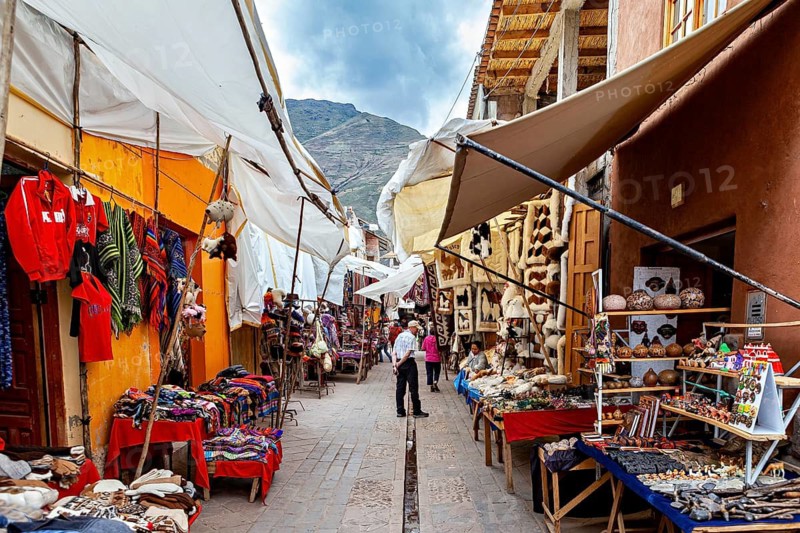 A colorful market with traditional Peruvian textiles and Andes in the background, the city of Ollantaytambo in the Andes of Peru