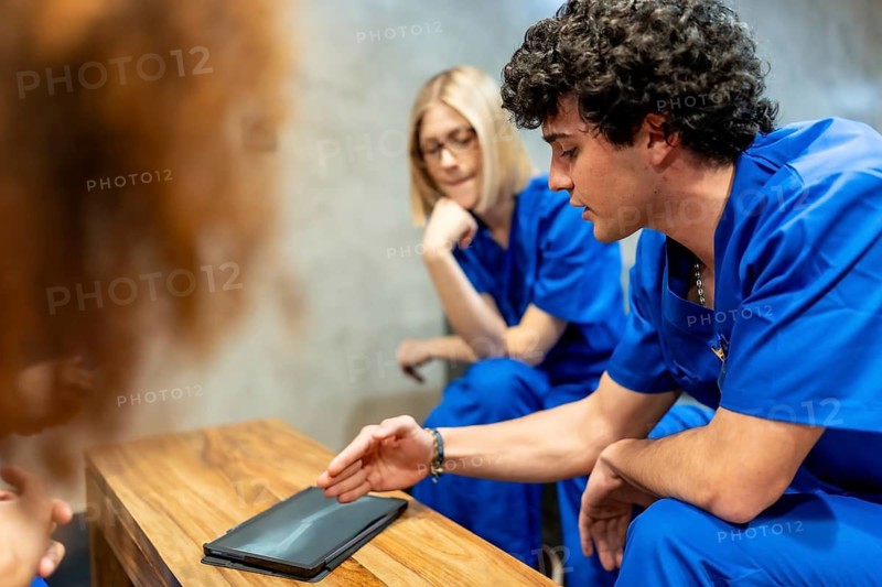 Medical students collaborating and learning, analyzing an x ray image on a digital tablet, fostering teamwork and education in a modern healthcare learning environment