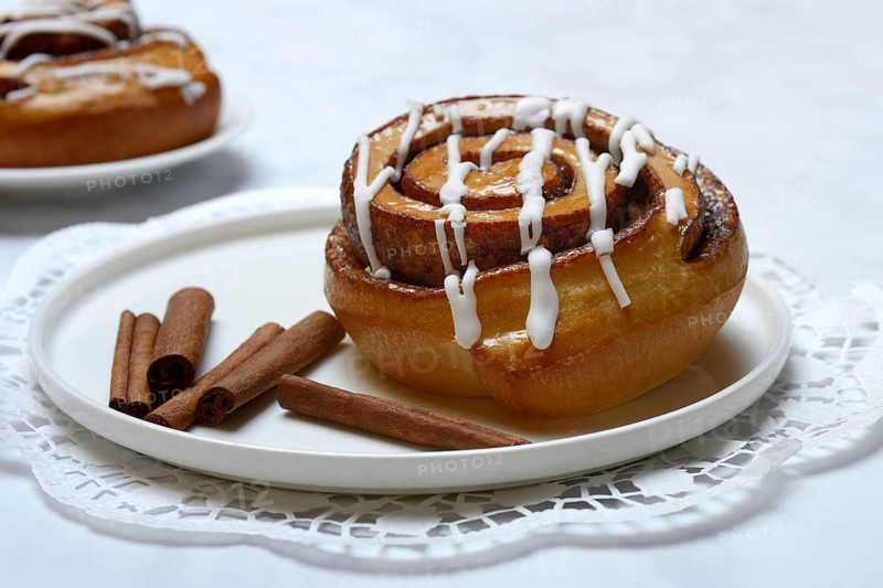 Cinnamon roll on plate and cinnamon sticks