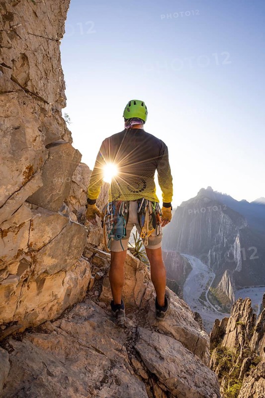A mountaineer practices climbing and rappelling at Eagle's Nest in Monterrey, Mexico, equipped with safety gear, surrounded by breathtaking rugged cliffs and a stunning valley view