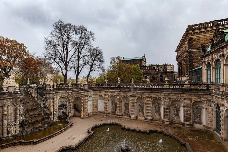 The majestic Palace Zwinger in Dresden, Germany, showcases exquisite Baroque architecture with intricate stone sculptures and elegant fountain, sets against a cloudy sky backdrop
