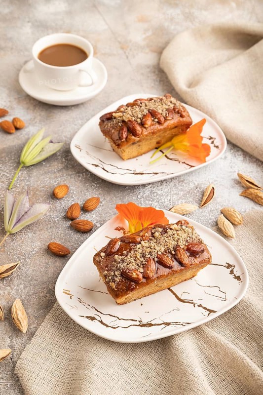 Caramel and almond cake with cup of coffee on brown concrete background and linen textile. side view, close up