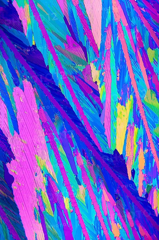 Vibrant microscopic image displaying the crystalline structure of Adipic acid, featuring striking shades of pink, blue, and green