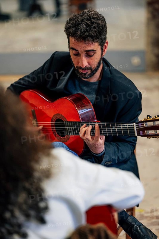 From above male friends playing guitars at table in music studio