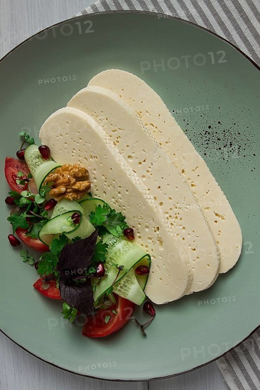 Sliced Imeruli cheese, Georgian cheese, with vegetables, top view, no people