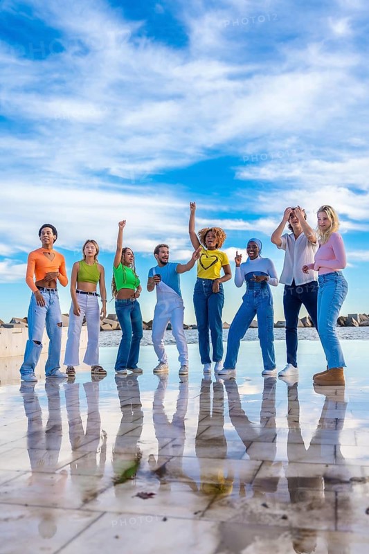 Vertical photo of a multiracial group of spontaneous young people dancing together outdoors