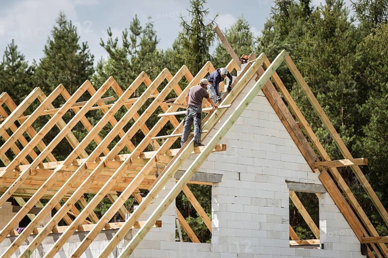 Two men work on the roof of house construction