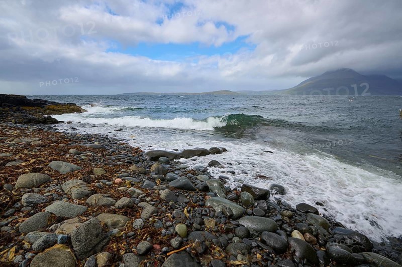 Waves break on rocky beach with mountains in the background and clouds in the sky, Elgol Beach, Elgol, Isle of Skye, Scotland, United Kingdom, Great Britain