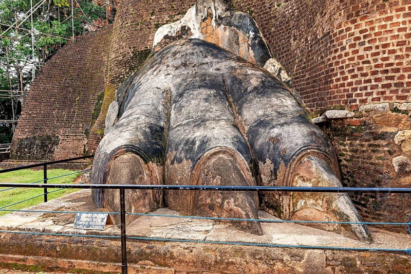 Large stone sculpture in the shape of a claw in front of an old brick wall, The Lion Gate at Lion Rock near Sigiriya in Sri Lanka
