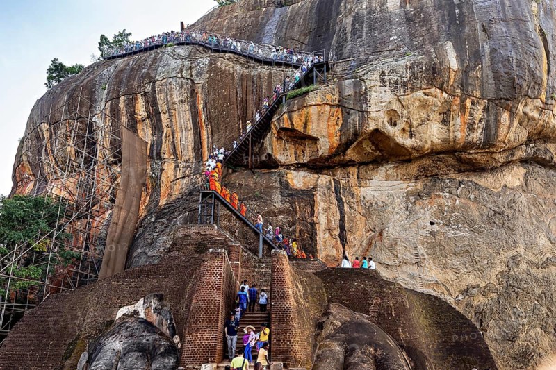 People climb a steep path nestled in a majestic rocky landscape, The Lion Rock near Sigiriya in Sri Lanka