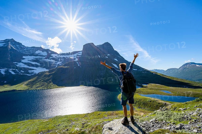 Hiker stretches his arms in the air, in front of mountain landscape with lake Giklingdalsvatnet, Sun Star, Flatvaddalen high valley, side valley of Innerdalen, Sunndal, Møre og Romsdal, Vestlandet, Norway