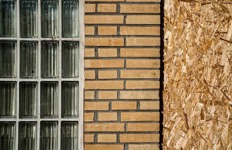 Old building with brick walls and a window covered with OSB panels