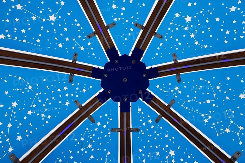 Close-up of backlit blue tinted plexiglass and curved wood panels canopy decorated with white starry vault theme motifs inside cocoon rocking chair made by Olivier Landreville, Horizon Art Installation, Ile des Moulins, Old Terrebonne, Quebec, Canada
